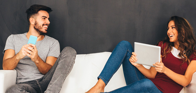 Man and woman happily watching shows on separate devices